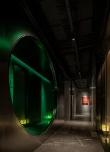 A modern, industrial-style corridor with concrete walls and flooring, accented with green lighting.