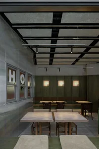 A minimalist cafe interior with wooden benches and tables, leather seating, and metal accents.