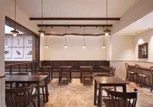 A modern restaurant interior with wooden furniture and tiled flooring.