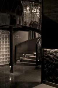 Interior design of a modern restaurant with black stairs and reflective metal wall.