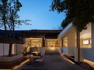 A night exterior view of a coffee shop featuring stone, concrete, and tiled elements.