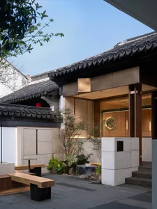 Glazed entryway of a hotel with wooden benches and granite planters