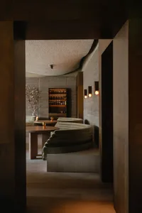 Modern industrial-style restaurant lounge featuring exposed concrete walls, curved seating, and warm lighting.