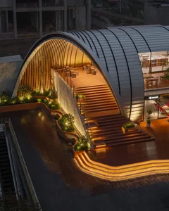 An illuminated, modern public space with metal architectural elements and plants.