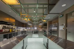 Modern industrial kitchen with marble countertops, industrial-style lighting, and stainless steel appliances.