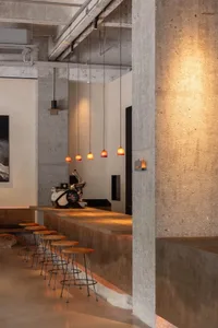 Interior design of an industrial-style coffee shop bar featuring concrete materials and pendant lighting.