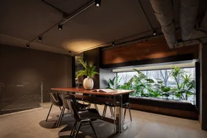 Modern, industrial-style commercial space featuring wood tables, steel chairs, and glass windows.