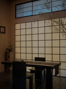 A serene wooden living room featuring paper panels, plants, and minimalist furniture