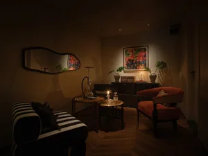 A minimalist living room with wooden floors, fabric seating, and glass tables.
