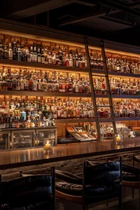 An industrial-style bar with metal shelves, wooden seating, and glass bottles.