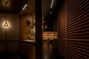 A dimly lit bar with wooden walls and shelves filled with bottles.