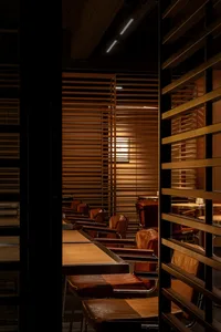 A row of brown leather restaurant seating with wood tables and metal legs.
