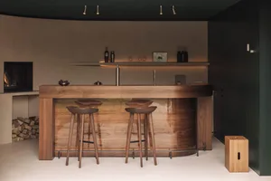 Modern residential bar area with wooden elements, stools, and a central island