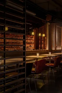 A modern restaurant bar with wooden tables, metal chairs, and a well-stocked back bar.