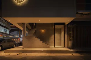 An illuminated retail storefront with concrete stairs leading inside.