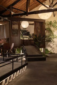 Industrial-style restaurant interior with concrete and wooden elements and large spherical lights.