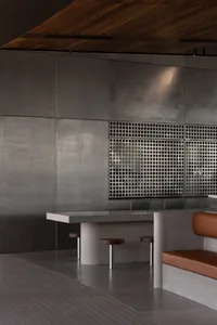A sleek, modern bar area with a concrete table and backdrop, featuring minimalist design and industrial elements.
