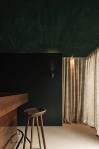 Bar stool made of wood with a curtain backdrop, featuring modern design elements.