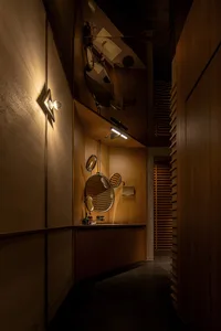 A modern bathroom featuring wooden walls and ceiling with industrial-style wall lights.