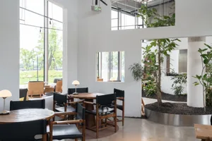 Modern cafe interior with wooden furniture and green plants.