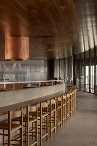 A minimalist restaurant interior featuring concrete, wood, and metal materials.