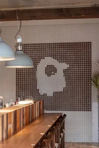 A wooden coffee shop counter featuring tiled walls.