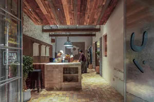 一間餐廳吧台採用工業風設計，搭配木質元素與裸露的天花板橫樑。