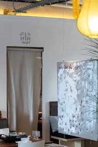 Modern industrial restaurant bathroom featuring a canvas artwork with footprints and text.