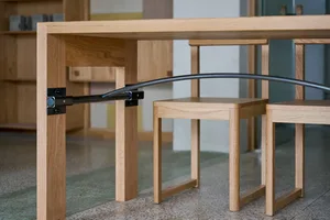 A minimalist table with glass top and wooden legs, accompanied by simple wooden chairs.