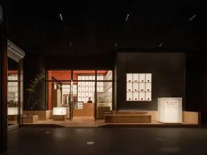 A modern storefront with a glass facade and warm interior lighting.