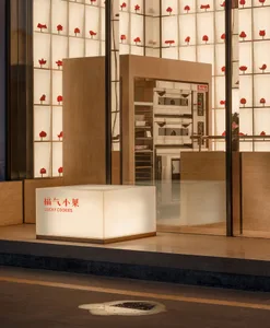 A modern retail storefront with a glass exterior and a cube-shaped illuminated sign