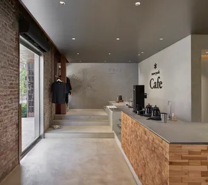 一間極簡工業風格的咖啡廳，設有混凝土吧台與木質元素。