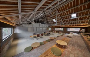 Industrial-style co-working space featuring exposed concrete flooring, brick walls, and rustic wooden furniture.