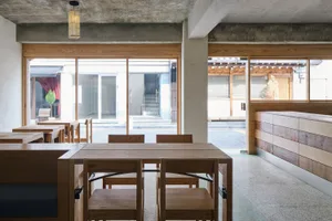 A modern restaurant interior with wooden furniture and concrete ceiling