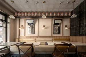 A restaurant interior with concrete walls, wooden tables and booths, and terrazzo flooring.