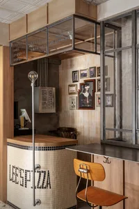 工業風餐廳廚房，配有木質吧台、金屬吧凳，以及玻璃展示窗。