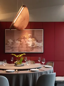 Modern dining room interior with glass and metal features, including a round table, chairs, and hanging light fixture.