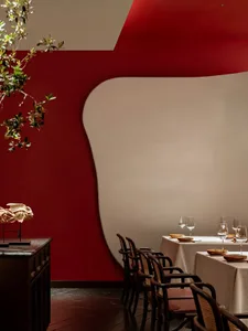 A modern restaurant interior with red velvet walls and white furniture.