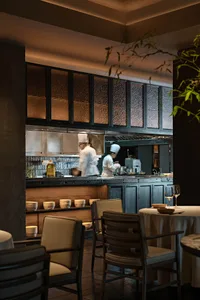 A modern restaurant kitchen with open concept design, featuring wooden materials and chefs preparing food.