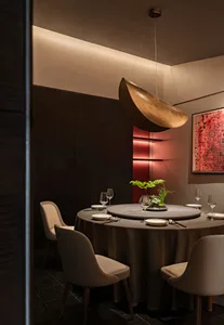 A modern restaurant interior with metallic pendant lighting and red lighting accents.