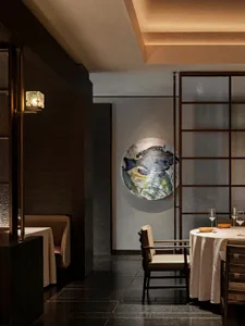 A modern restaurant interior with white walls and black floor, featuring minimalist design and a round white painting with fi