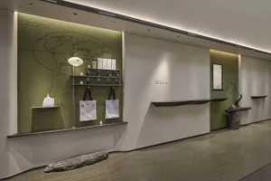 A modern retail store interior featuring a sleek wooden counter against a white wall, with shelves showcasing various product