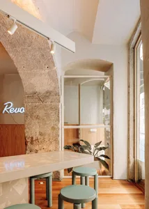 A modern restaurant featuring concrete and wooden materials with a glass barrier and neon signage.