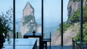 A modern restaurant interior with glass walls overlooking a scenic mountain view.