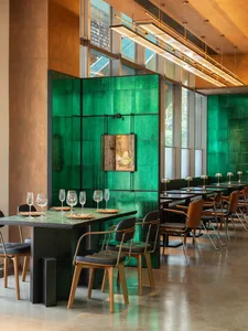 Modern restaurant interior with a prominent green-tile backdrop.