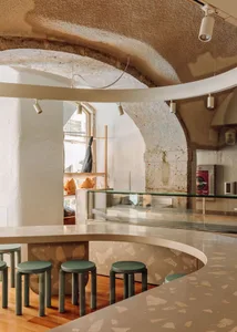 Minimalist coffee shop with terrazzo counter and green stools