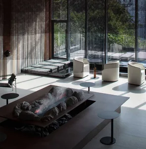 A modern living room with a metal coffee table, chairs, and fireplace.