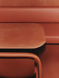 A close-up view of a modern restaurant booth upholstered in leather and cork material, featuring an integrated tabletop surfa