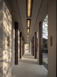 A minimalist corridor with concrete walls and lighting fixtures, featuring tall vertical columns and a well-defined pathway.