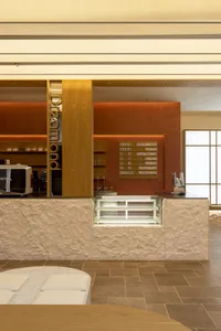 A modern coffee shop with a stone counter and wooden shelving.